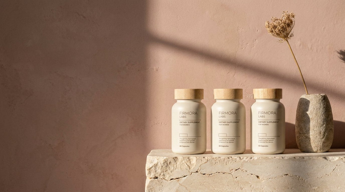 Three Firmora bottles against a dusty rose wall